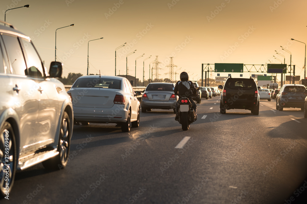 Traffic jam on a hot summer evening. Highway and road junction. Sunset cars and moto - obrazy, fototapety, plakaty 