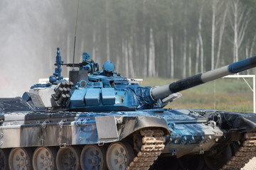 Military or army tank ready to attack and moving over a deserted battle field terrain