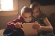 © Wavebreak Media - Siblings using tablet computer while sitting on sofa at home