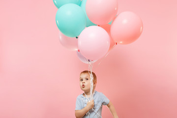 Wall Mural - Playful little cute child baby boy holding bunch of colorful air balloons, celebrating birthday holiday party on pastel color pink background. Family day kids children childhood lifestyle concept.