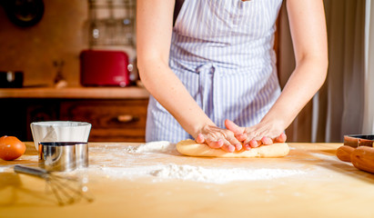 Making dough by female hands on wooden table