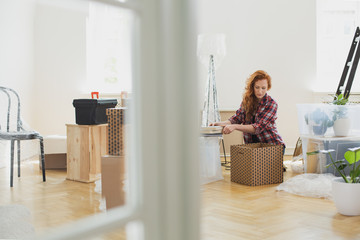 Woman packing books into carton boxes while moving out to new home