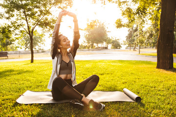 Cute fitness sports woman in park outdoors listening music with earphones.