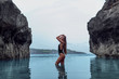 Beautiful girl in a black swimsuit in a blue lagoon among the rocks
