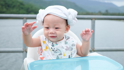 Wall Mural - The Asian cute baby wear the diaper hat sit near the river with happiness face.