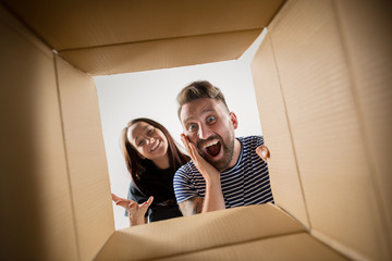 The surprised man and woman unpacking, opening carton box and looking inside. The package, delivery, surprise, gift lifestyle concept