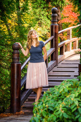 young blond european woman on a wooden bridge in a city park