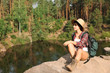 © New Africa - Young woman on rock near lake and forest. Camping season