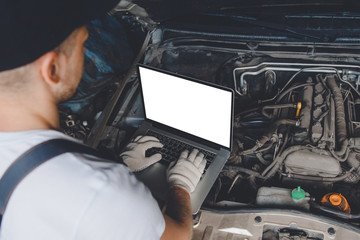 Professional car mechanic using electrnoic diagnostic equipment laptop in auto repair service.