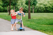Two little Caucasian preschool children fighting hitting each other. Boy and girl can not share one scooter. Older sibling brother not giving his toy to younger sister. Communication problems.