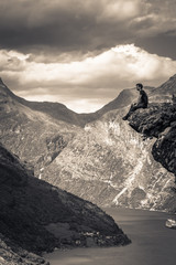 Wall Mural - Geiranger - July 30, 2018: Traveler at Flydalsjuvet viewpoint looking down at the stunning UNESCO Geiranger fjord, Norway