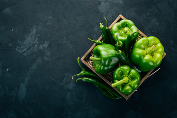 Wall Mural - Fresh green pepper and chili pepper in a wooden box. Top view. Free space for text.