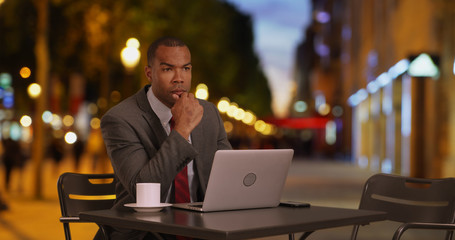 African-American professional finishing up work on computer at cafe in Paris