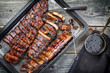 Barbecue spare ribs St Louis cut with hot honey chili marinade as top view in a rustic skillet
