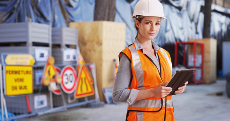 Confident woman contractor posing confidently with tablet on construction site