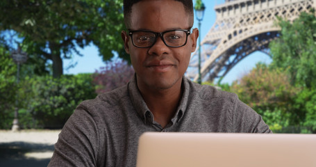 Wall Mural - Portrait of handsome black male sitting with laptop near Eiffel Tower