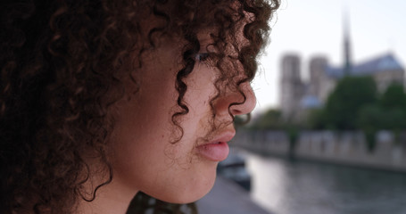 Depressed young woman stares at the Seine on gloomy day in Paris