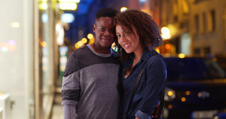 Wall Mural - Happy African American couple pose for a portrait in the city at night