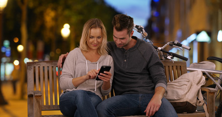 Happy young couple taking a selfie on the Champs-Elysees at night