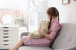 Little autistic girl sitting on sofa with toy at home