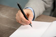 © New Africa - Writer signing autograph in book at table, closeup