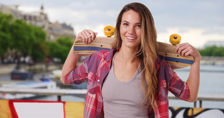 Wall Mural - Happy Caucasian girl in Paris holding skateboard on her shoulders