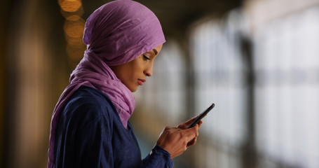 Wall Mural - An attractive young Muslim woman using the phone turns to smile