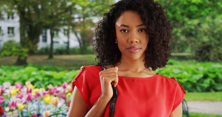 Wall Mural - Millennial Black woman in park standing next to tulip garden in red dress
