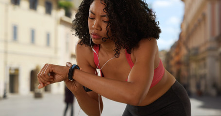 Wall Mural - Woman staying fit while on vacation in Rome checking her fitness tracker on run