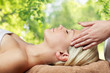 beauty, wellness and relaxation concept - close up of beautiful young woman lying with closed eyes and having face or head massage in spa over green natural background