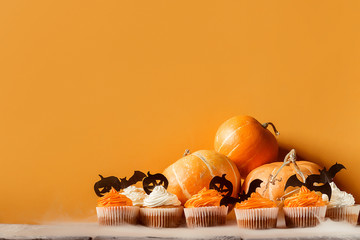 cupcakes and pumpkins to celebrate halloween on a background with space for text