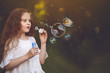 © ulkas - Surprised girl blowing out a soap bubble in the shape of a dog or cat. Magic, wish, new year concept.