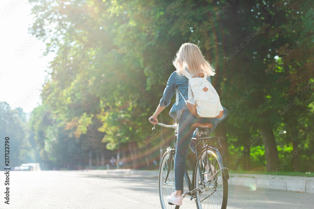 back view of student with backpack riding bicycle on street Stock Photo ...