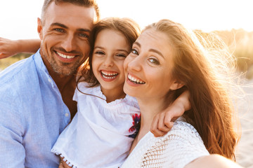 Poster - Parents having fun together outdoors at the beach with their daughter.