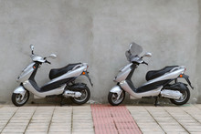 Two Scooters Parked Near The Wall