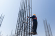 worker at altitude strengthens the pillars from rebar, on the blue sky background. candid, real people