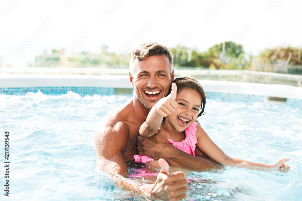 Photo of happy family father with daughter smiling, while swimming in pool outdoor during summer vacation - obrazy, fototapety, plakaty 