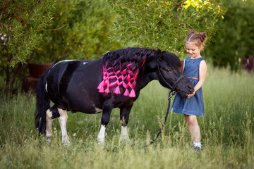 Cute little girl and pony in a beautiful park