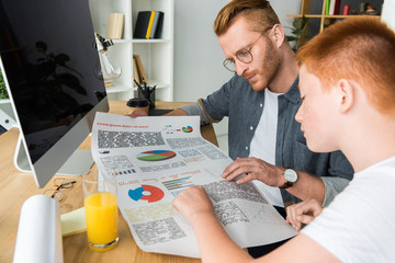 Wall Mural - father and son looking at diagram at table at home