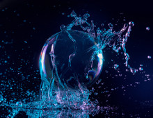 Blue And Purple Water Splashing On A Transparent Ball In A Dark Background