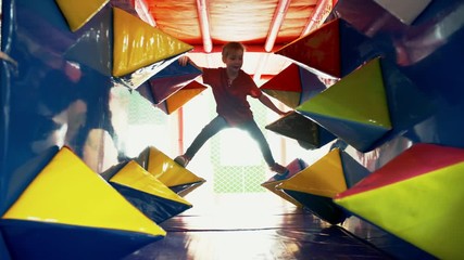 Wall Mural - Front view of excited little girl of elementary school age having fun in play tunnel when spending time in playroom