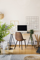 Modern computer screen on an industrial desk by a white wall in a warm, sunny study space of a teenager bedroom interior