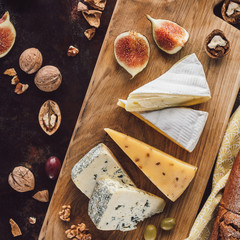 Wall Mural - food composition with assorted cheese, figs and hazelnuts on dark tabletop