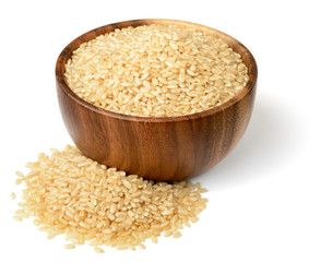 uncooked brown rice in the wooen bowl, isolated on the white background