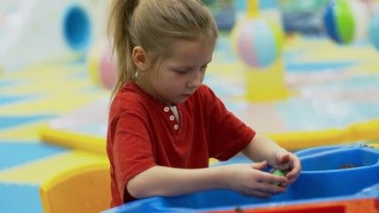 Wall Mural - Medium shot of little girl of primary school age developing fine motor skill by playing with sand molds in playroom