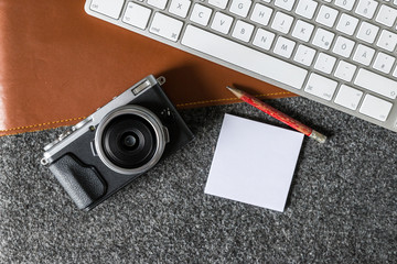 Wall Mural - Office environment with computer keyboard, camera and blank page on desk as flat lay from above