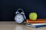 Fototapeta Tematy - manzana en libros con despertador y pizarra vacía, regreso a la escuela
