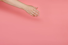 The Female Hand On A Pink Background Stretches To Something Diagonally. Copy Space.