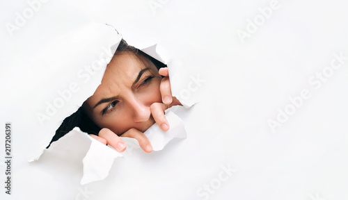 Cuadros en Lienzo Portrait of a woman looking through the hole in white paper