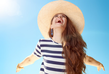 Wall Mural - happy young woman in straw hat rejoicing against blue sky